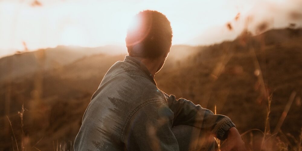 man in field looking to horizon